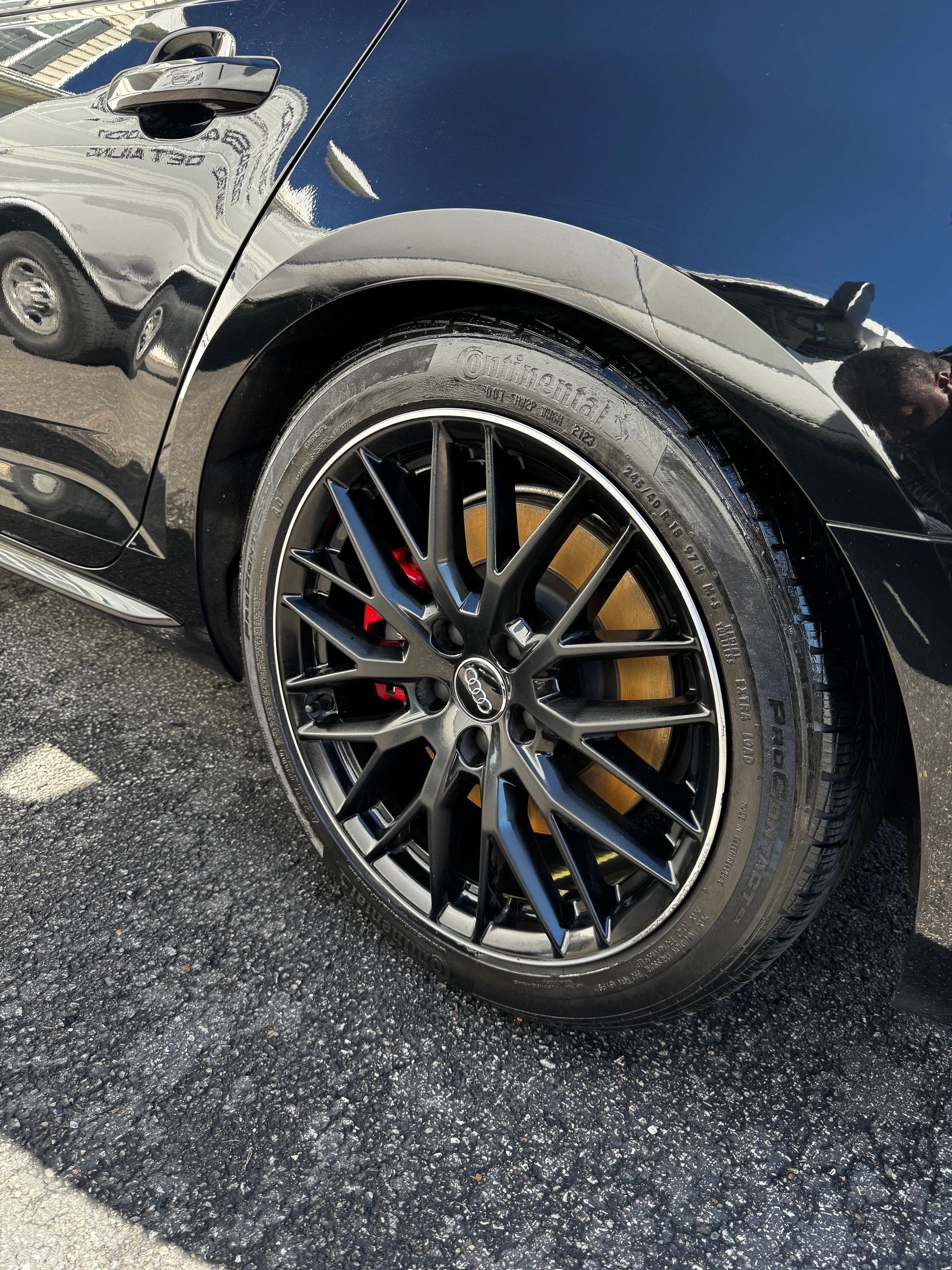 Obsidian Detailing — black sports car wheel with gold brakes